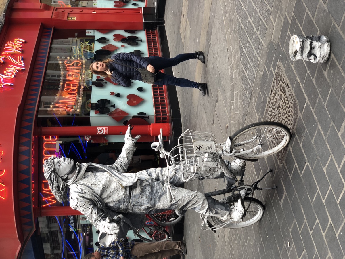 Silver street performer posed beside a bicycle
